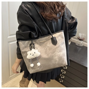 Detail of grey marble tote bag with black leather straps and plush cloud charm accessory