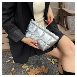 Chic silver quilted clutch bag styled on a wooden bench with fall leaves in the background