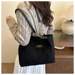 Detail der schwarzen gesteppten Shopper-Tasche mit goldenem Logo und Kettenriemen