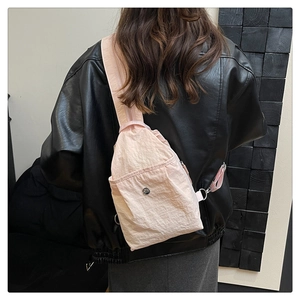 Pink nylon crossbody sling bag worn over a black leather jacket for a stylish look