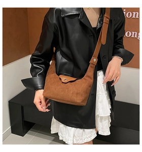 Brown suede crescent bag shown as a crossbody view on a model with a long leather strap