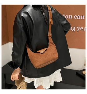 Detailed texture of brown suede crescent bag with adjustable leather shoulder strap