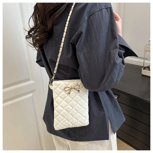 Détail du sac bandoulière matelassé blanc avec boucle nœud dorée et bandoulière chaîne