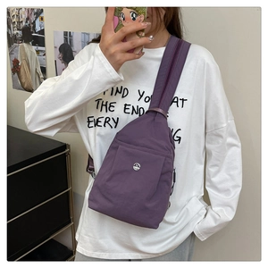 Detail view of the purple nylon chest bag showing the metallic M logo and snap pocket