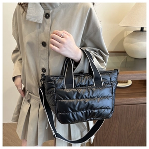 Dettaglio della borsa tote nera trapuntata con texture imbottita e manici a righe