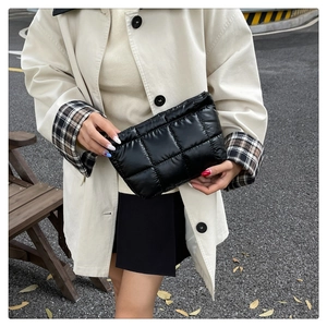 Detail of black quilted down clutch bag with waterproof nylon and glossy finish