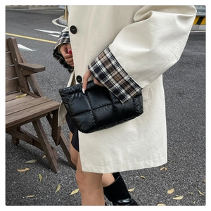 Vue détaillée d'une pochette matelassée noire avec broderie carrée et texture rembourrée