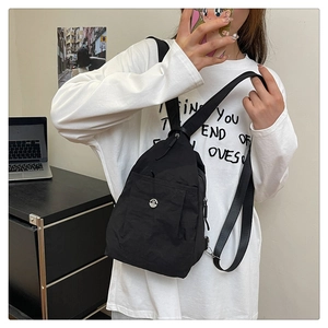 Close-up of multifunctional black nylon mini backpack with a metallic M logo and silver hooks