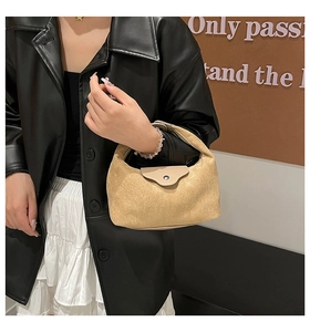 Detail view of the khaki suede texture and metal buckle on the minimalist dumpling bag