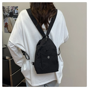 Detailed view of women's nylon backpack showing metal zipper and circular silver logo