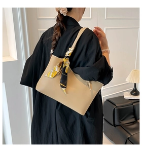 Detail of beige tote bag featuring a decorative yellow silk scarf on the shoulder strap