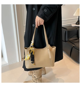 Detail of beige bucket tote bag with floral silk scarf handle in modern interior setting