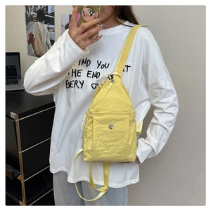 Modern bright yellow nylon sling bag shown on model with adjustable shoulder straps