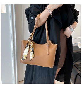 Detail of a brown leather bucket bag featuring an elegant vintage print silk scarf handle