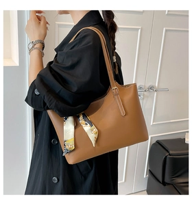Detailed view of brown textured leather tote bag featuring an elegant printed silk scarf accent