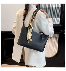 Black leather tote bag with silk scarf detail shown as a shoulder bag on a model