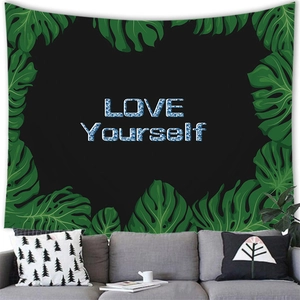 Tapisserie feuilles de monstera avec texte 'LOVE YOURSELF' suspendue sur mur gris