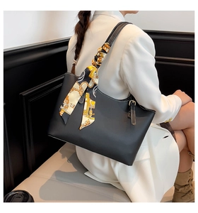 Detail of black tote bag featuring matte leather texture and elegant printed silk scarf
