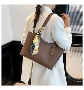 Detail of brown leather tote with contrast stitching and decorative vintage silk scarf