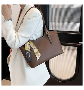 Brown tote bag with silk scarf detail on model wearing a white business suit