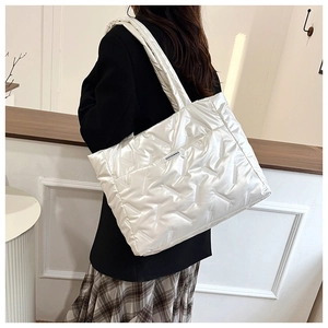 Detailed back view of a white quilted puffer tote bag worn by a model in a modern room