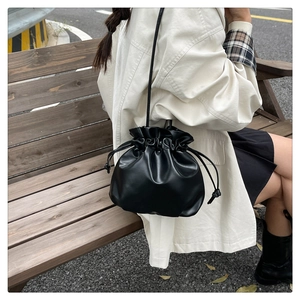 Detail of a black drawstring bucket bag showing premium leather texture and folds