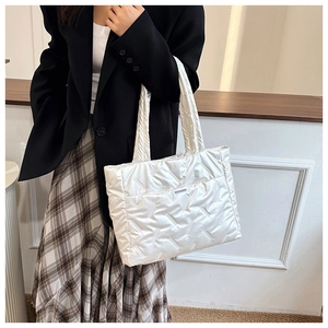 Close-up of quilted white puffer tote bag featuring fashion label and soft padded texture