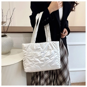 Close-up of silver quilted tote bag showing textured V-pattern and fashion woven label