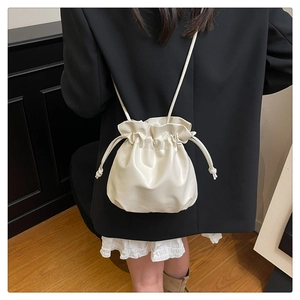 Chic cream white drawstring bucket bag shown worn by model as a stylish crossbody purse