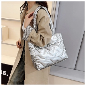 Detail of silver quilted tote bag with metallic finish and padded down texture shown on model