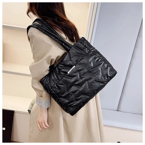 Close-up of a black quilted tote bag with a fashion label and stylish geometric texture