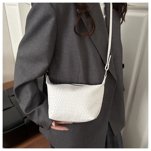 Close-up of white woven textured PU leather crossbody bag with minimalist slim shoulder strap