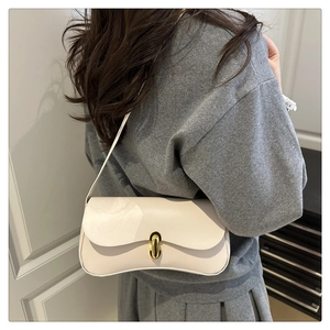 Detailed view of a white leather baguette shoulder bag with golden metallic buckle