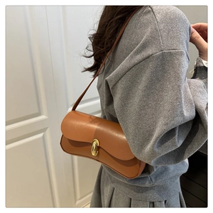 Caramel leather underarm bag with gold metal buckle shown on model in casual style