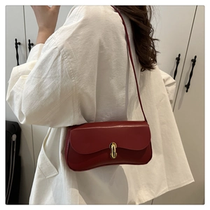 Gros plan d'un sac à bandoulière bordeaux avec rabat ondulé et fermoir doré sur un modèle
