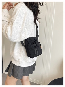 Détail de la bandoulière réglable et de la fermeture à cordon de ce sac en nylon noir