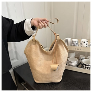 Close-up of soft beige suede texture and mini coin purse charm on a tote bag