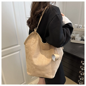 Close-up of a beige faux suede tote bag featuring a minimalist Hobo bucket style design