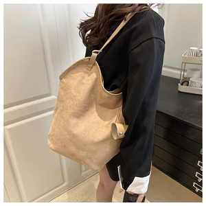 Detail of camel suede tote bag showing soft texture and decorative round pouch