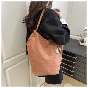 Detail of caramel brown suede tote bag featuring smooth texture and thin leather strap
