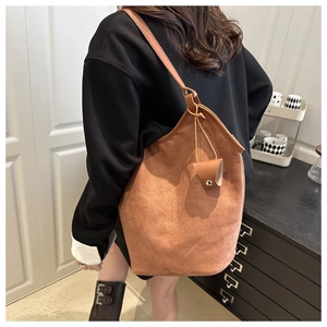 Brown suede tote bag shown on shoulder with minimalist bucket design and matte texture