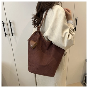 Detail of dark brown suede tote bag with matching pouch on model's shoulder