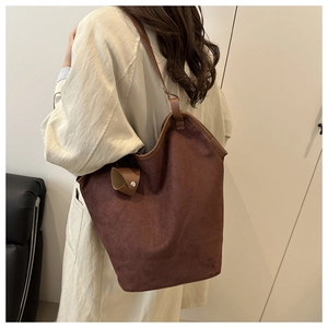 Deep brown suede bucket bag shown on shoulder, highlighting large capacity and soft texture
