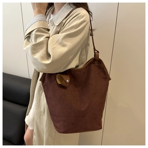 Detailed texture of dark brown suede tote bag featuring leather buckle charm detail