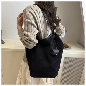 Close-up of minimalist black suede tote bag with matching mini pouch and slim shoulder strap