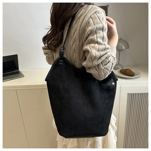 Close-up of black suede tote bag with slim shoulder straps in a home office setting