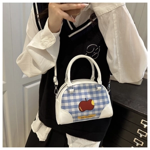 Detail of blue plaid handbag featuring leather trim and cartoon apple graphic