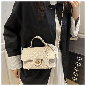 Close-up of quilted cream handbag with silk scarf handle and golden twist-lock closure