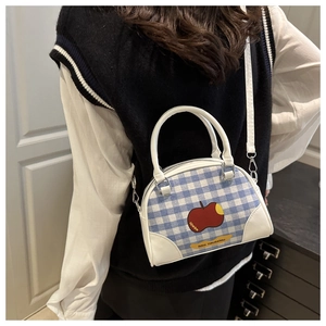 Detail of blue plaid mini bag featuring a red apple print and white leather strap