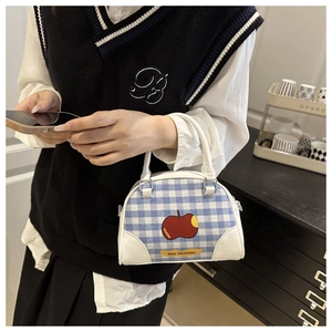 Close-up of blue gingham bowling bag with apple motif and white leather patchwork detail